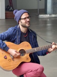 Un homme avec un bonnet gris jouant de la guitare