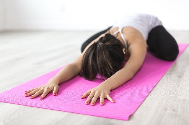 Une femme en train de pratiquer le Yoga en étirement sur son tapis